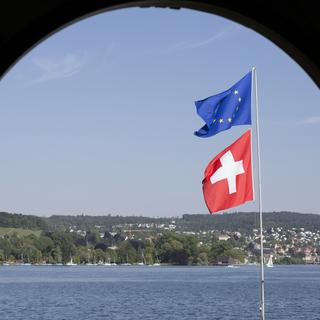 Un drapeau européen et un drapeau suisse flottent dans le vent au bord du lac de Zurich. [Keystone - Gaëtan Bally]