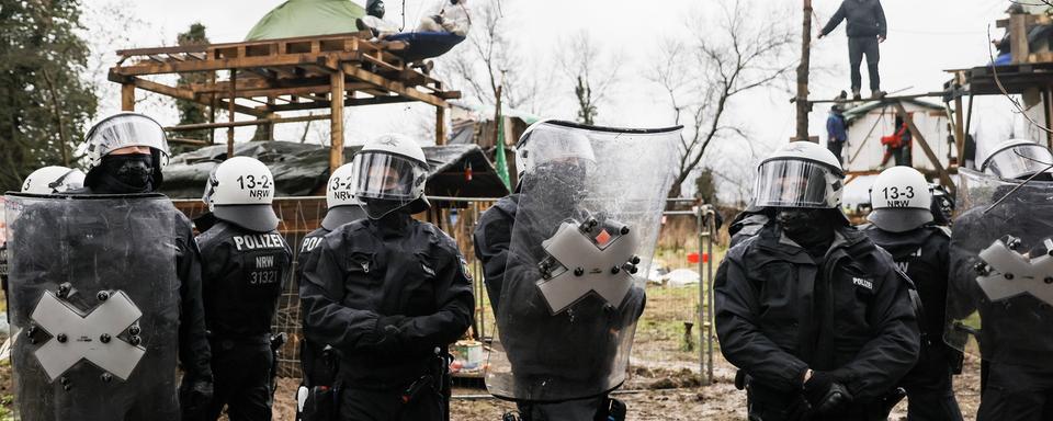 Des officiers de polices montent la garde durant l'opération de délogement des activistes pour le climat établis à Lüzerath. [EPA/Keystone - RONALD WITTEK]