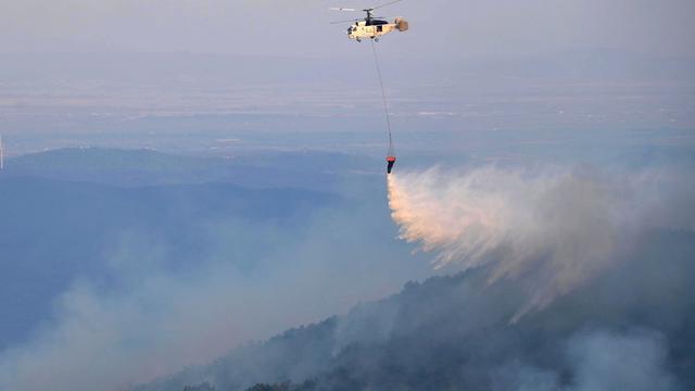 Un hélicoptère de lutte contre les incendies largue de l'eau dans la région de Leptokarya, Evros, nord de la Grèce, le 26 août 2023. [Keystone - EPA/DIMITRIS ALEXOUDIS]