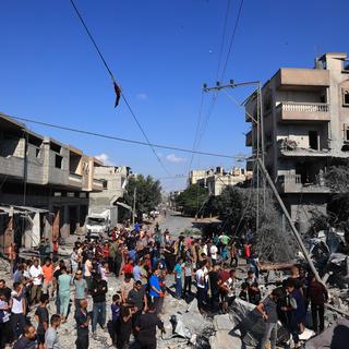Des Palestiniens sont rassemblés autour d'un immeuble effondré à la suite d'un bombardement israélien à Rafah, au sud de la bande de Gaza. [AFP - Saïd Khatib]