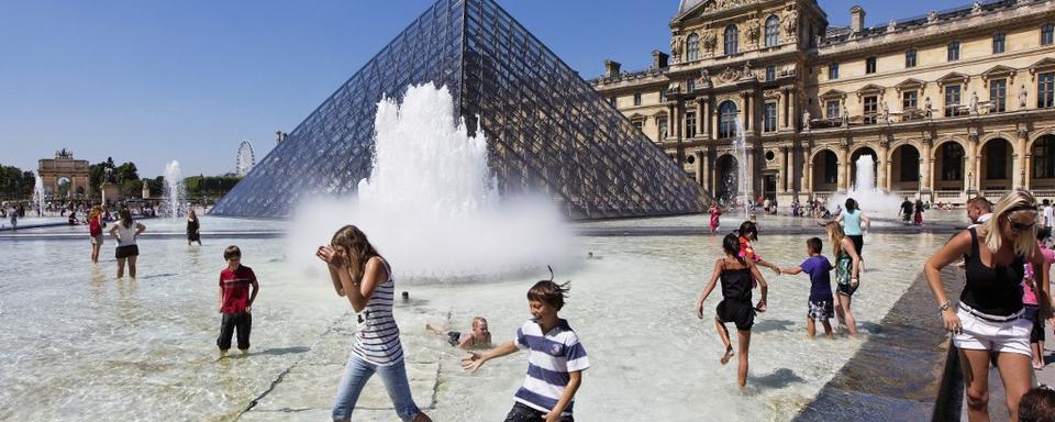 On se rafraîchit devant la pyramide du Louvre à Paris. [Keystone - Bruno de Hogues]