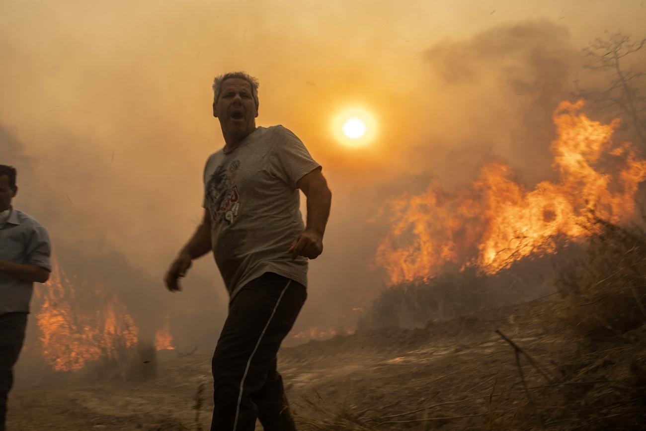 Un habitant de l'île de Rhodes en Grèce en proie aux flammes. [AP Photo - Petros Giannakouris]