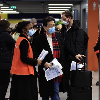 Des passagers chinois attendent de se faire tester au Covid à leur arrivée à l'aéroport Charles de Gaulle, à Paris. [AP Photo/Keystone - Aurelien Morissard]