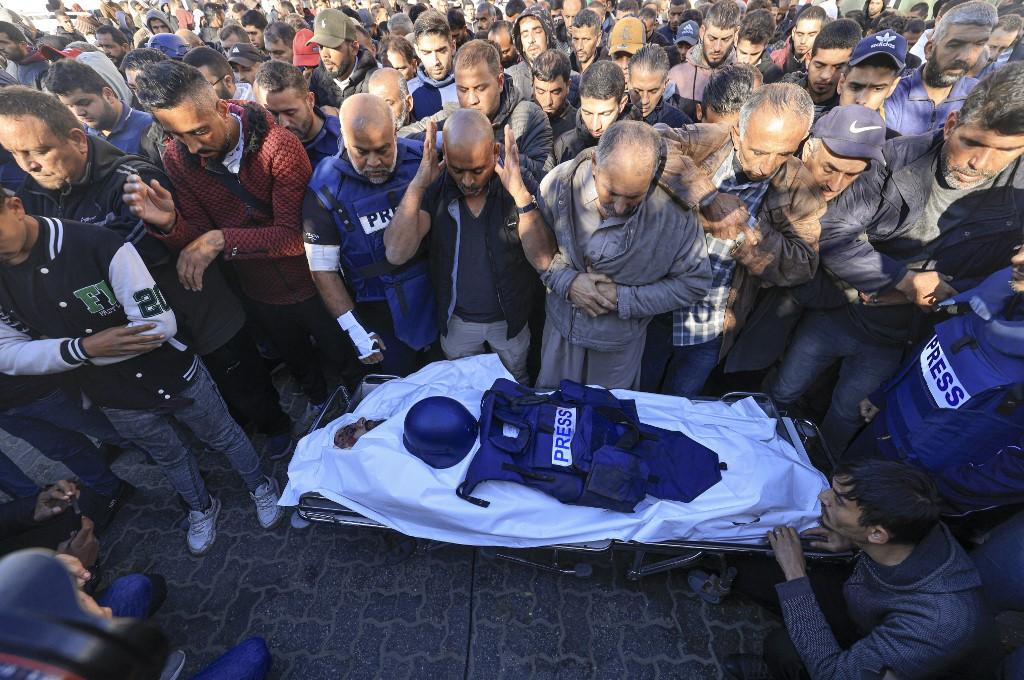 Des collègues et des membres de la famille prient sur le corps du caméraman d'Al Jazeera Samer Abu Daqa, qui a été tué lors d'un bombardement israélien, lors de ses funérailles à Khan Younès, dans le sud de la bande de Gaza, le 16 décembre 2023. [AFP - Mahmud HAMS]
