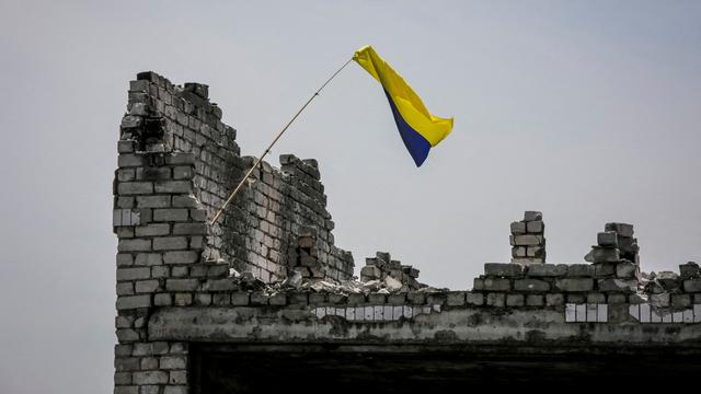 Un drapeau ukrainien sur les ruines d'un village récemment repris par les forces ukrainiennes. [Reuters - Oleksandr Ratushniak]