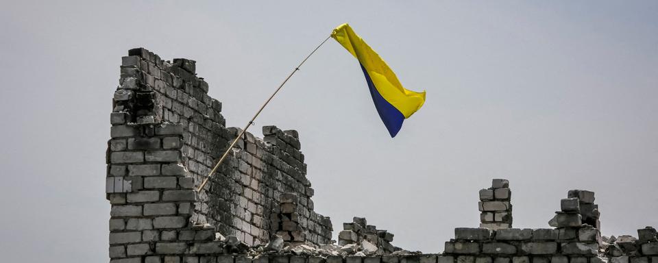 Un drapeau ukrainien sur les ruines d'un village récemment repris par les forces ukrainiennes. [Reuters - Oleksandr Ratushniak]