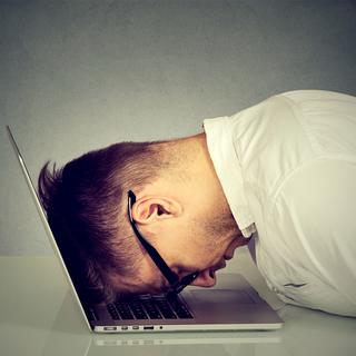 Un homme se cogne la tête contre son ordinateur. [Depositphotos - Slphotography]