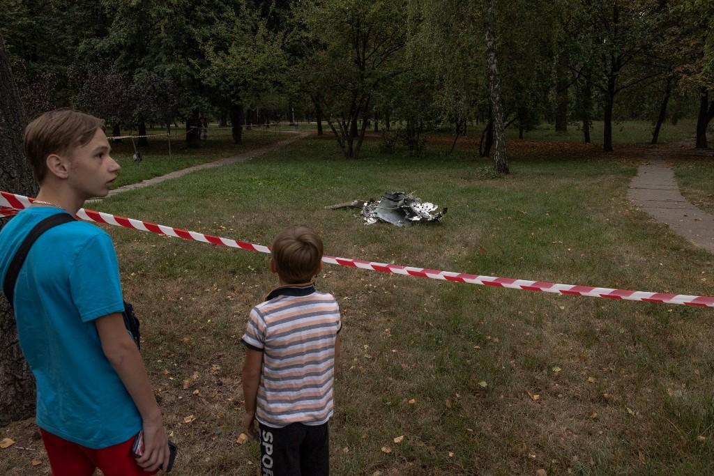 Des garçons regardent les débris d'un missile après une attaque à Kiev le 30 août 2023. [AFP - Roman Pilipey]