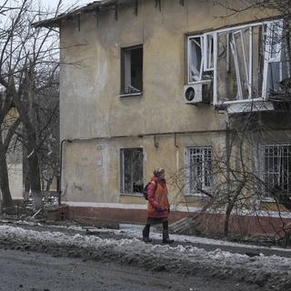 Une femme passe devant un bâtiment endommagé après une attaque à la roquette sur un quartier résidentiel de Kramatorsk, dans la région de Donetsk, dans l'est de l'Ukraine, le 2 février 2023. [Keystone - Sergey Shestak / EPA]