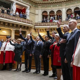 Le nouveau Conseil fédéral prête serment, de gauche à droite: Viola Amherd, Guy Parmelin, Ignazio Cassis, Karin Keller-Sutter, Albert Roesti, Elisabeth Baume-Schneider, et les nouveaux élus Beat Jans et le chancelier Viktor Rossi, flanqués des huissiers Antoine Maillard, à droite, et Mario Gonzalez, à gauche, après l'élection du Conseil fédéral par l'Assemblée fédérale, le 13 décembre 2023. [KEYSTONE - PETER SCHNEIDER]