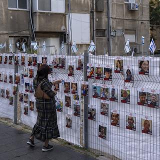 Une femme devant les portraits des otages kidnappés lors de l'attaque du 7 octobre. [Keystone/AP Photo - Oded Balilty]