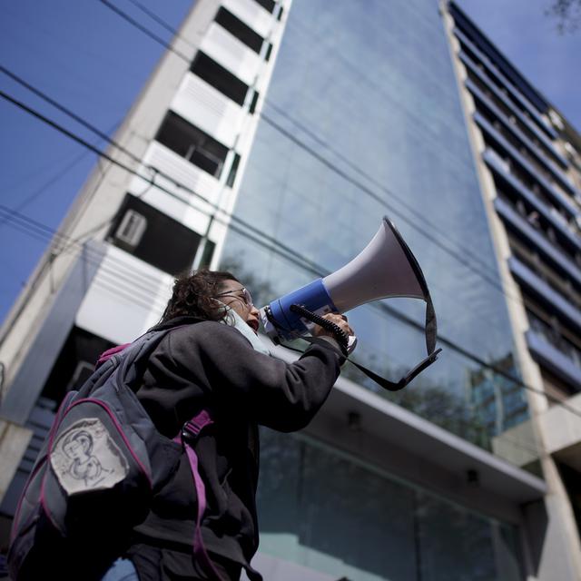 Une femme s'exprimant avec un mégaphone en face des bureaux du Fonds monétaire international (FMI) à Bueno Aires, Argentine (image d'illustration). [Keystone/AP Photo - Victor R. Caivano]