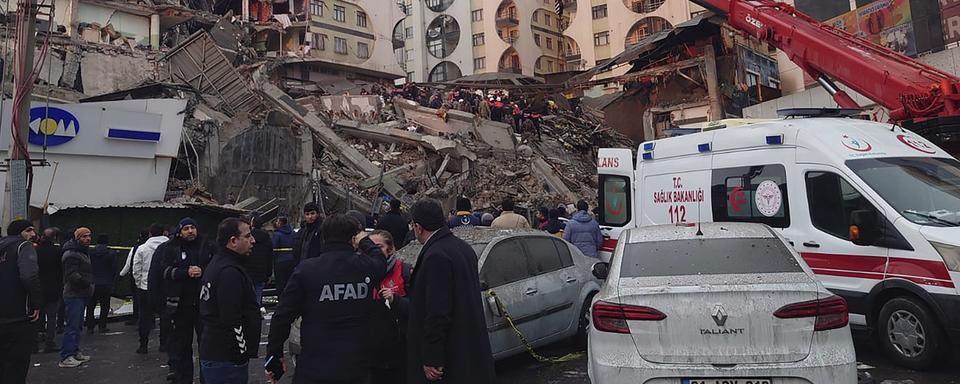 De nombreux immeubles se sont effondrés à cause du séisme, comme ici à Diyarbakir en Turquie. [Keystone - AP Photo/Mahmut Bozarsan]