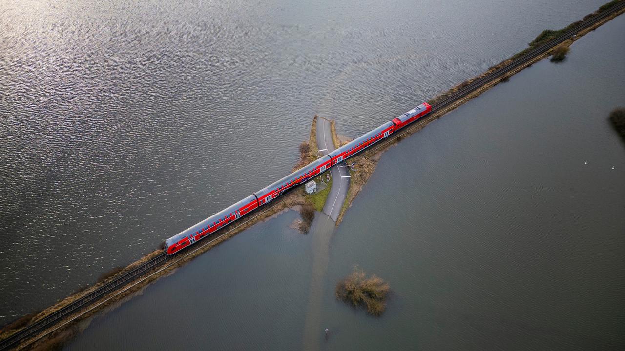 Jeudi 28 décembre: un train régional circule sur un remblai encerclé par l'eau près de Francfort-sur-le-Main, dans le centre de l'Allemagne. Cette zone près d'Eichen est presque chaque année inondée, raison pour laquelle ce tronçon est surélevé. [Keystone - Andreas Arnold]