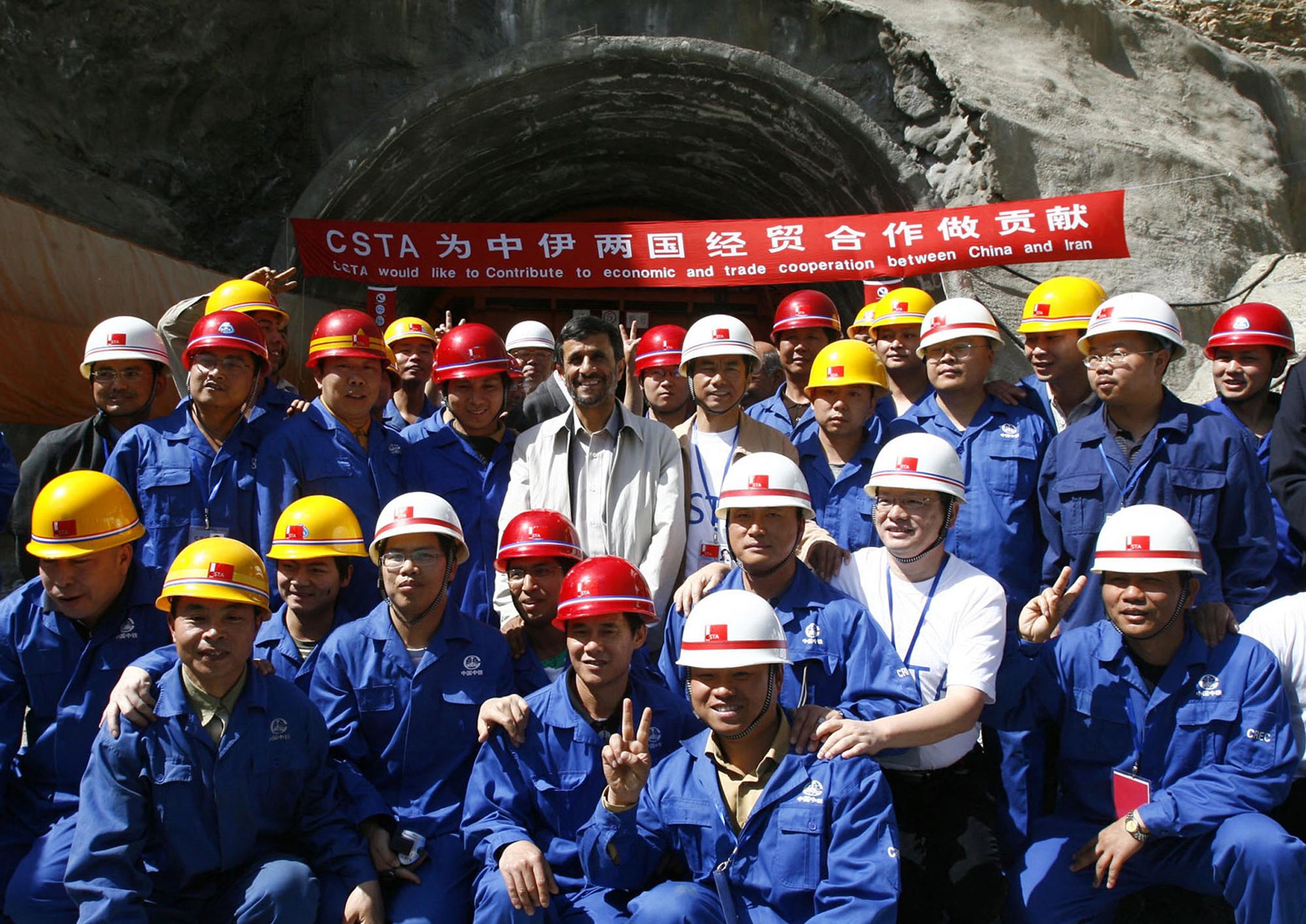 Le président iranien de l'époque Mahmoud Ahmadinejad pose pour une photo avec des ouvriers et des ingénieurs chinois à l'extérieur d'un tunnel sur la route entre Téhéran et Chalus, au nord-ouest de Téhéran, le 29 juin 2009, lors d'une visite d'inspection du projet "Autoroute du Nord". [afp - Amir Pourmand]