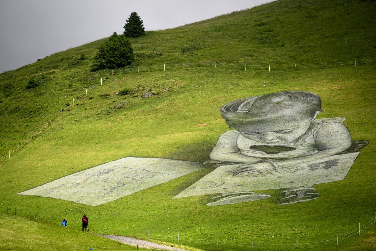 Oeuvre de Saype à Villars, représentant une petite fille qui dessine un paysage. [Keystone - Laurent Gilliéron]