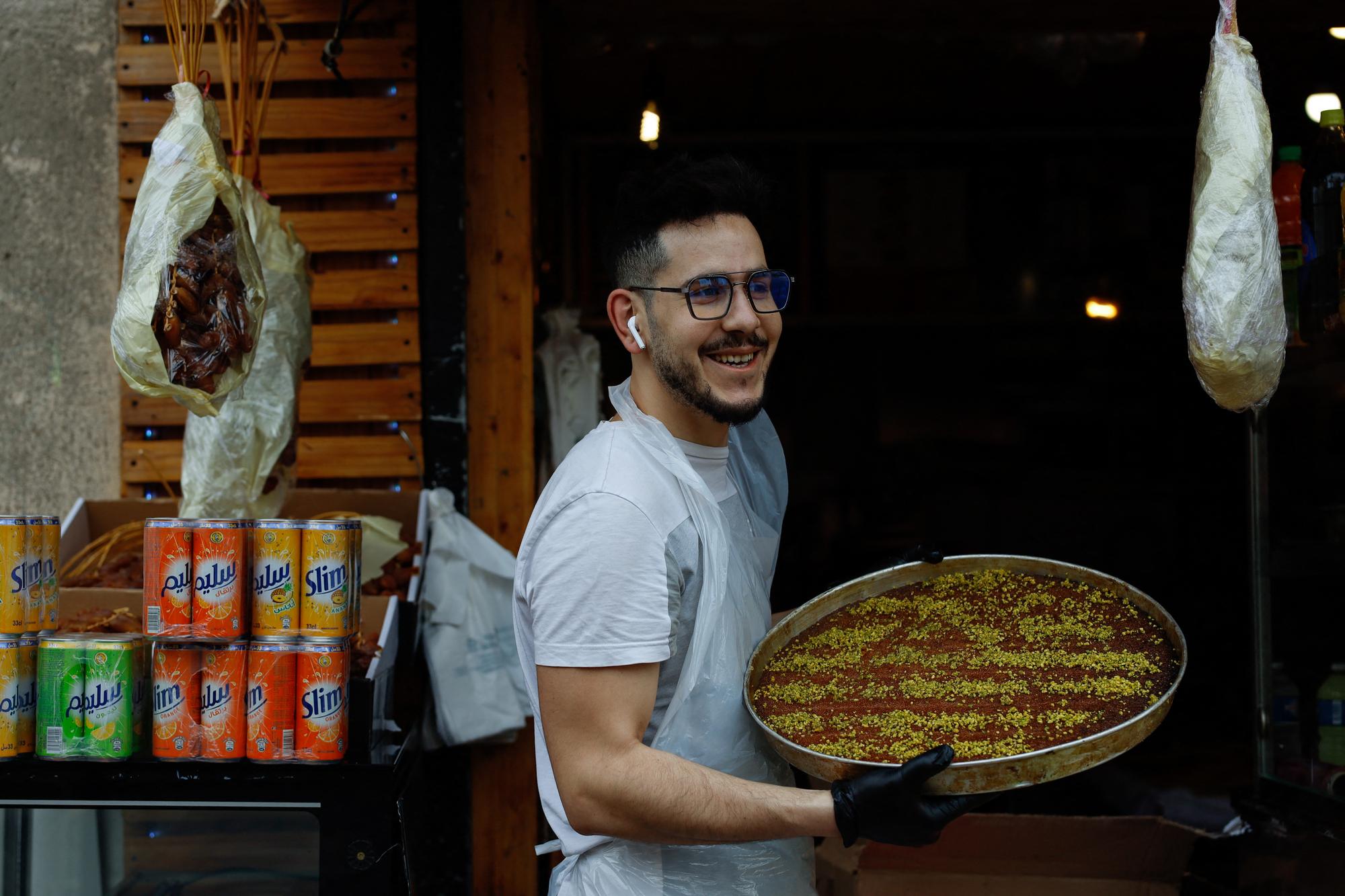 Un vendeur porte un plat de baklava dans une épicerie de Paris, le premier jour de ramadan, le 23 mars 2023. [AFP - Ameer Alhalbi]
