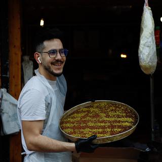 Un vendeur porte un plat de baklava dans une épicerie de Paris, le premier jour de ramadan, le 23 mars 2023. [AFP - Ameer Alhalbi]