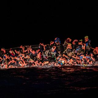 Des dizaines de migrants tombent à l'eau alors qu'ils luttent pour s'accrocher au côté d'un bateau en train de chavirer au large de la Tunisie (image d'archive). [Keystone/AP - Valeria Ferraro]