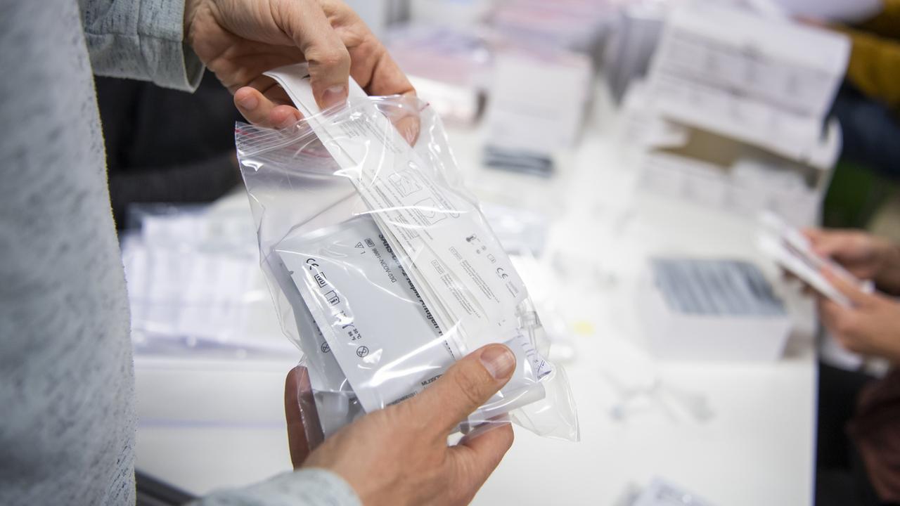Une personne prépare un sachet contenant un auto-test pour le dépistage du Coronavirus (Covid-19). [Keystone]