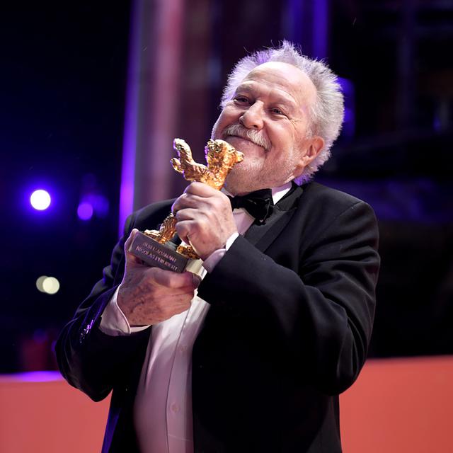 Le réalisateur Nicolas Philibert avec son Ours d'Or à Berlin, le 25 février 2023, pour son film "Sur l'Adamant". [Keystone - Markus Schreiber]