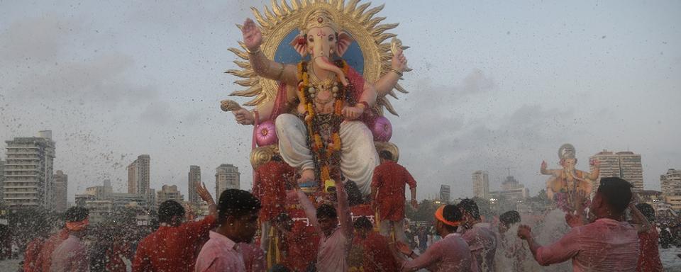 Des dévots indiens immergent des statues de Ganesh, le dieu hindou à tête d'éléphant qui représente la sagesse. [Keystone/AP Photo - Rafiq Maqbool]