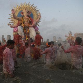 Des dévots indiens immergent des statues de Ganesh, le dieu hindou à tête d'éléphant qui représente la sagesse. [Keystone/AP Photo - Rafiq Maqbool]
