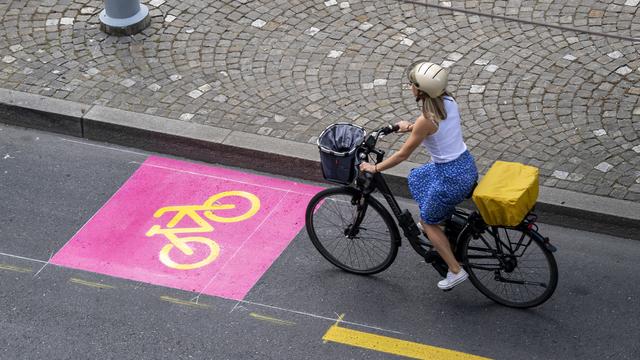 Une cycliste sur une piste cyclable à Genève [Keystone - Martial Trezzini]