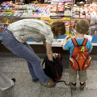 Une femme et un petit garçon dans un kiosk à journaux en Suisse (image d'illustration). [Martin Ruetschi]