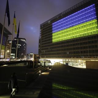 Les sièges du Conseil de l'UE et de la Commission européenne illuminés aux couleurs de l'Ukraine, le 24 février 2023. [EPA/Keystone - Olivier Hoslet]