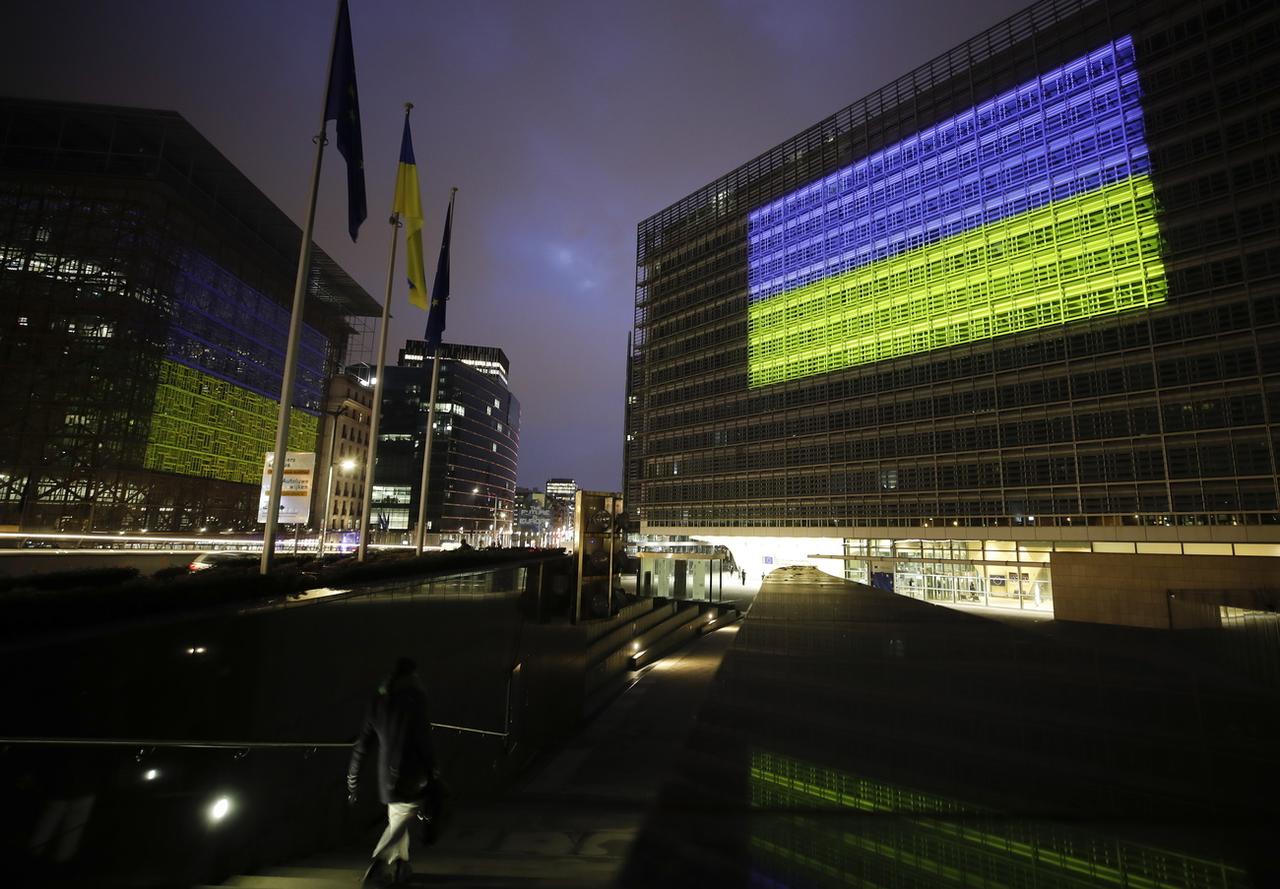 Les sièges du Conseil de l'UE et de la Commission européenne illuminés aux couleurs de l'Ukraine, le 24 février 2023. [EPA/Keystone - Olivier Hoslet]