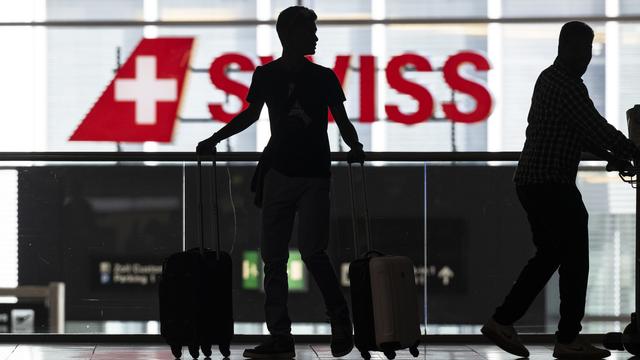 Un homme attend son vol au départ de l'aéroport de Zurich. [Keystone - Ennio Leanza]