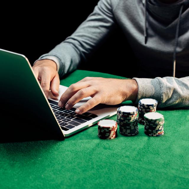 Gros plan sur les mains d'une personne qui joue au poker en ligne. [Depositphotos - VitalikRadko]