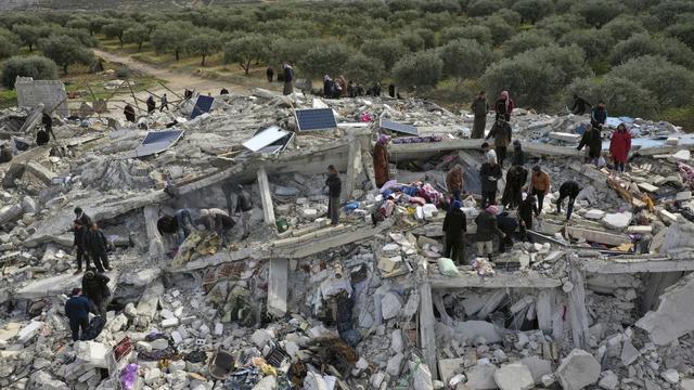 Des employés de la protection civile et des habitants fouillent les décombres de bâtiments effondrés dans la ville de Harim, près de la frontière turque, dans la province d'Idlib, en Syrie. [Keystone - Ghaith Alsayed]