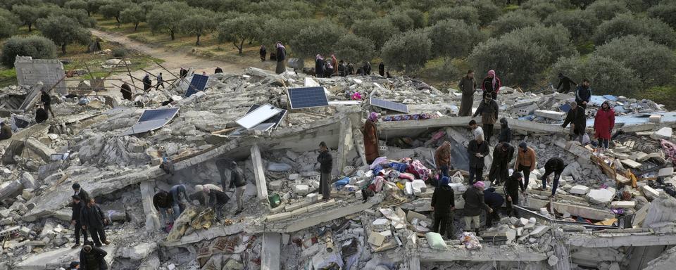 Des employés de la protection civile et des habitants fouillent les décombres de bâtiments effondrés dans la ville de Harim, près de la frontière turque, dans la province d'Idlib, en Syrie. [Keystone - Ghaith Alsayed]