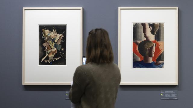 Une femme observe des tableaux de Kandinsky (à gauche) et d'Oscar Schlemmer lors de l'exposition "Gurlitt, un bilan" en septembre 2022 au Musée des Beaux-Arts de Berne. [Keystone - Anthony Anex]