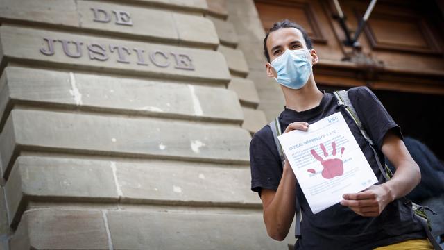 La justice genevoise doit revoir la condamnation d'un militant climatique qui avait peint des mains rouges sur la façade de Credit suisse lors d'une manifestation. [KEYSTONE - VALENTIN FLAURAUD]