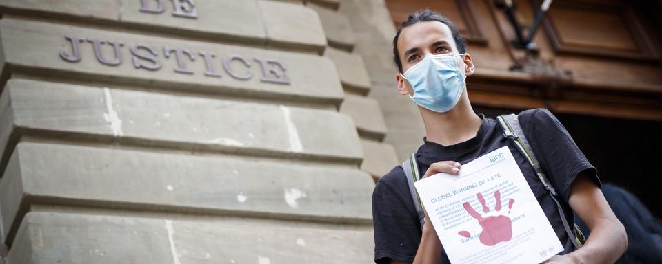 La justice genevoise doit revoir la condamnation d'un militant climatique qui avait peint des mains rouges sur la façade de Credit suisse lors d'une manifestation. [KEYSTONE - VALENTIN FLAURAUD]