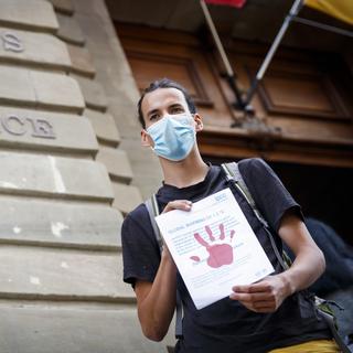 La justice genevoise doit revoir la condamnation d'un militant climatique qui avait peint des mains rouges sur la façade de Credit suisse lors d'une manifestation. [KEYSTONE - VALENTIN FLAURAUD]