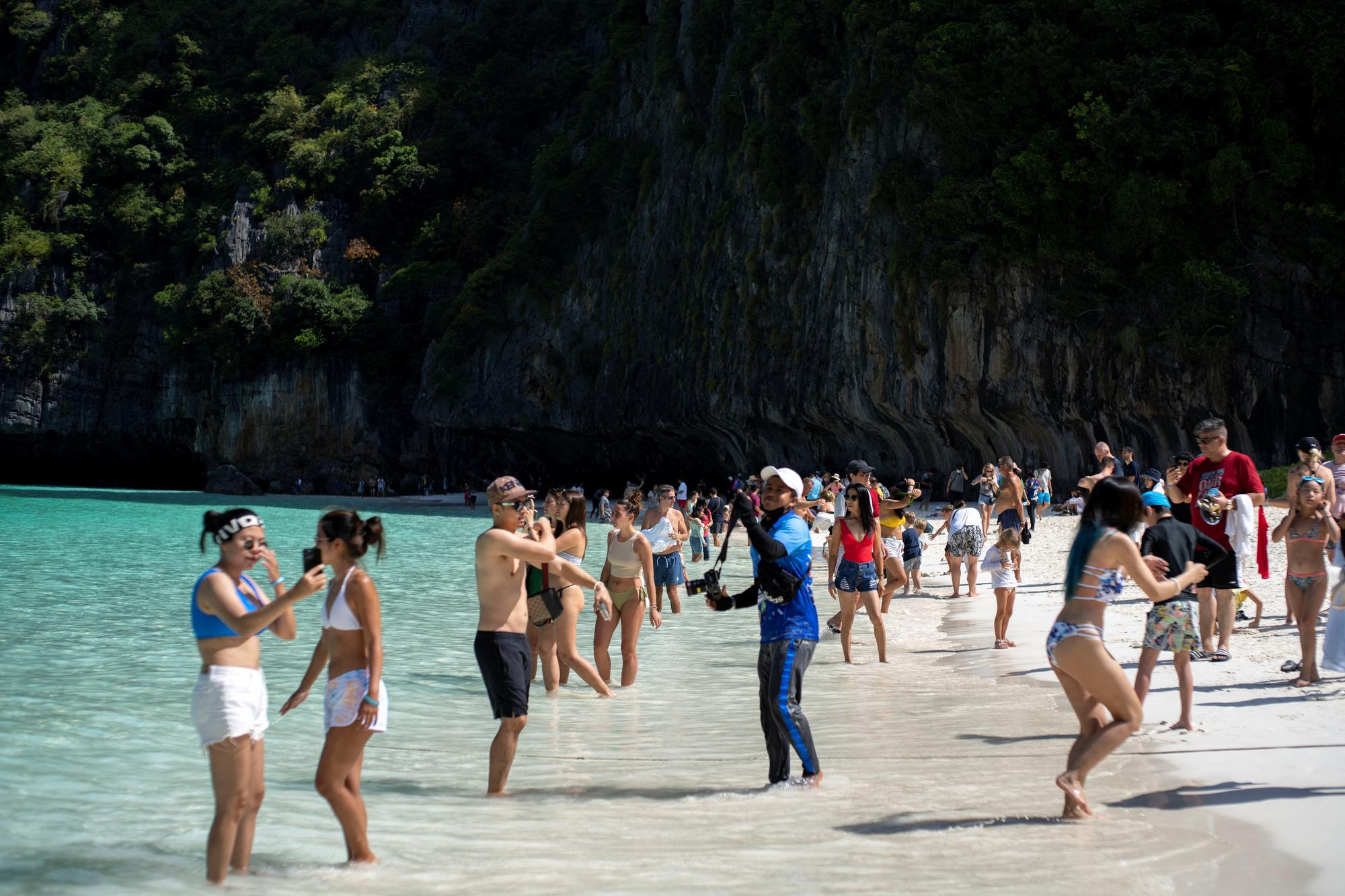Des touristes prennent la pose à la réouverture de la plage de Maya Bay, fermée pour laisser la nature récupérer. [Reuters - Athit Perawongmetha]