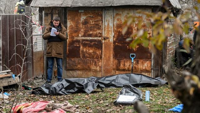 Des corps de civils ukrainiens examiné par un officiel (photo d'illustration). [NurPhoto via AFP - Dmytro Smoliyenko]