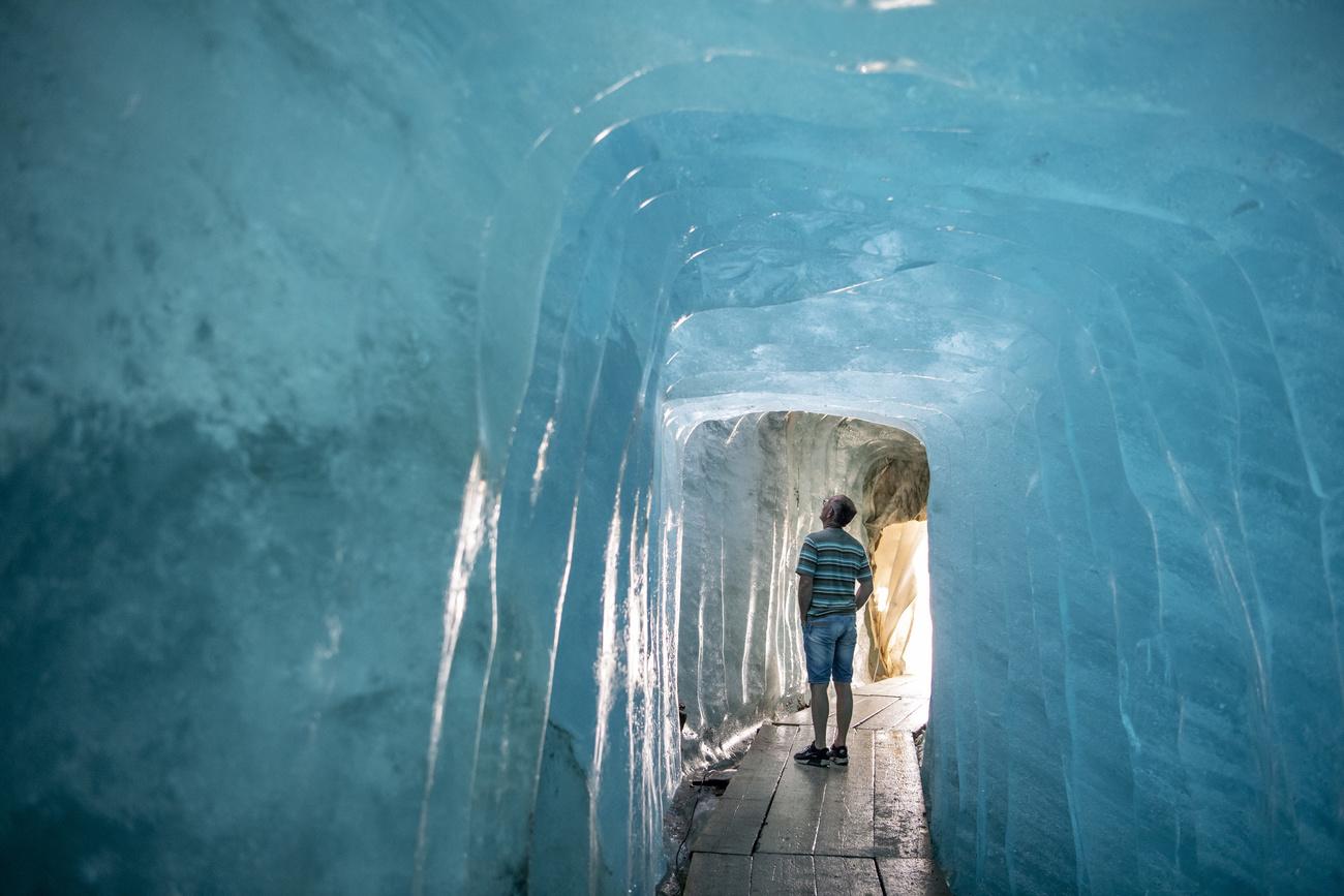 Un visiteur dans la grotte de glace du glacier du Rhône en juillet 2022. [Keystone - Urs Flueeler]