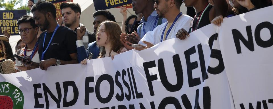 Des manifestants en marge de la COP28 sur le climat demandent la fin des énergies fossiles. [AP/Keystone - Peter Dejong]