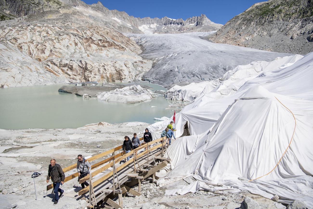 Des personnes visitent le glacier du Rhône recouvert de couvertures en juillet 2022. [Keystone - Urs Flueeler]