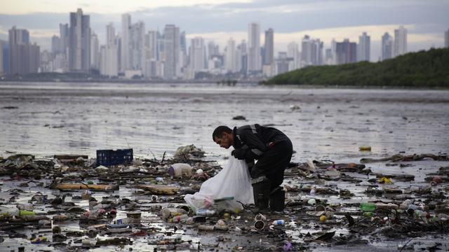 Une personne ramasse des déchets qui flottent dans la baie de Panama City, au Panama (image d'illustration). [Keystone/EPA - Carlos Lemos]