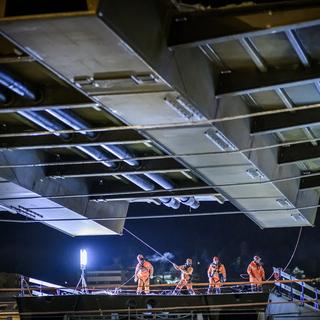Des ouvriers installant une pièce métallique sur le chantier de remplacement du Grand-Pont à La Chaux-de-Fonds. [Keystone - Gabriel Monnet]