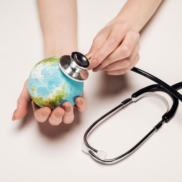 Gros plan sur une main qui ausculte une terre miniature avec un stéthoscope. [Depositphotos - VadimVasenin]