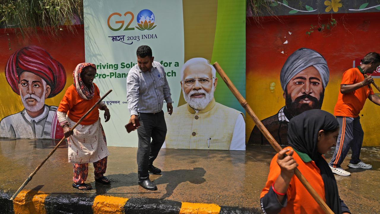 Des travailleurs municipaux indiens nettoient un trottoir en marge du futur sommet du G20 à New Dehli le week-end prochain. [Keystone/AP - Manish Swarup]