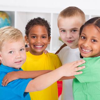 Un groupe de quatre enfants regarde la caméra en souriant. Ils et elle se tiennent dans les bras en cercle. [Depositphotos - Michael Jung]