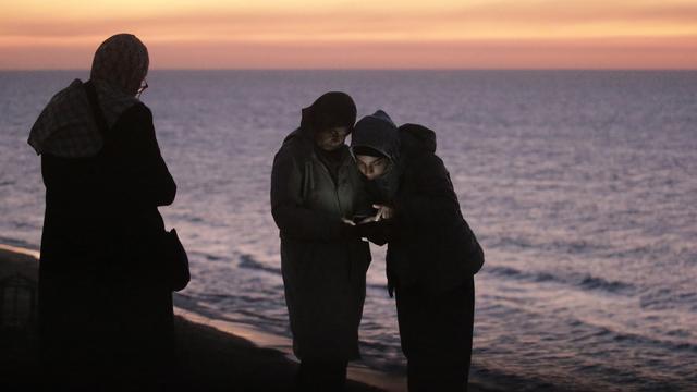 Des Palestiniennes cherchent du réseau sur une plage de Gaza. [Keystone - EPA/Mohamemd Saber]